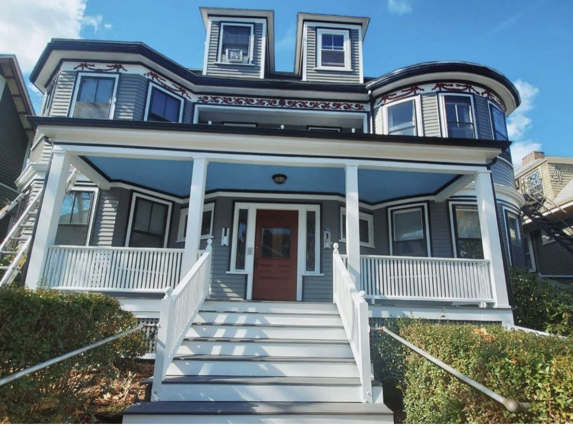 Victorian home with a blue and white exterior repaint and a wide front porch