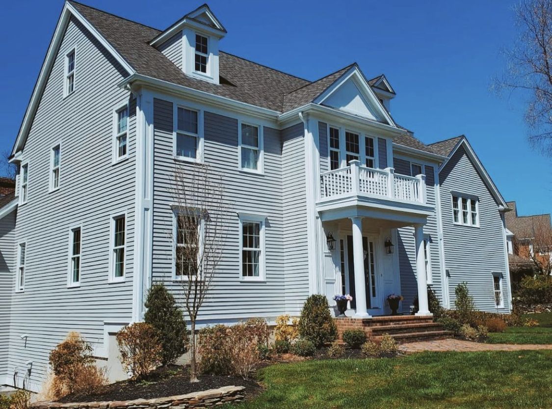 Gray colonial house with white trim after an exterior repaint