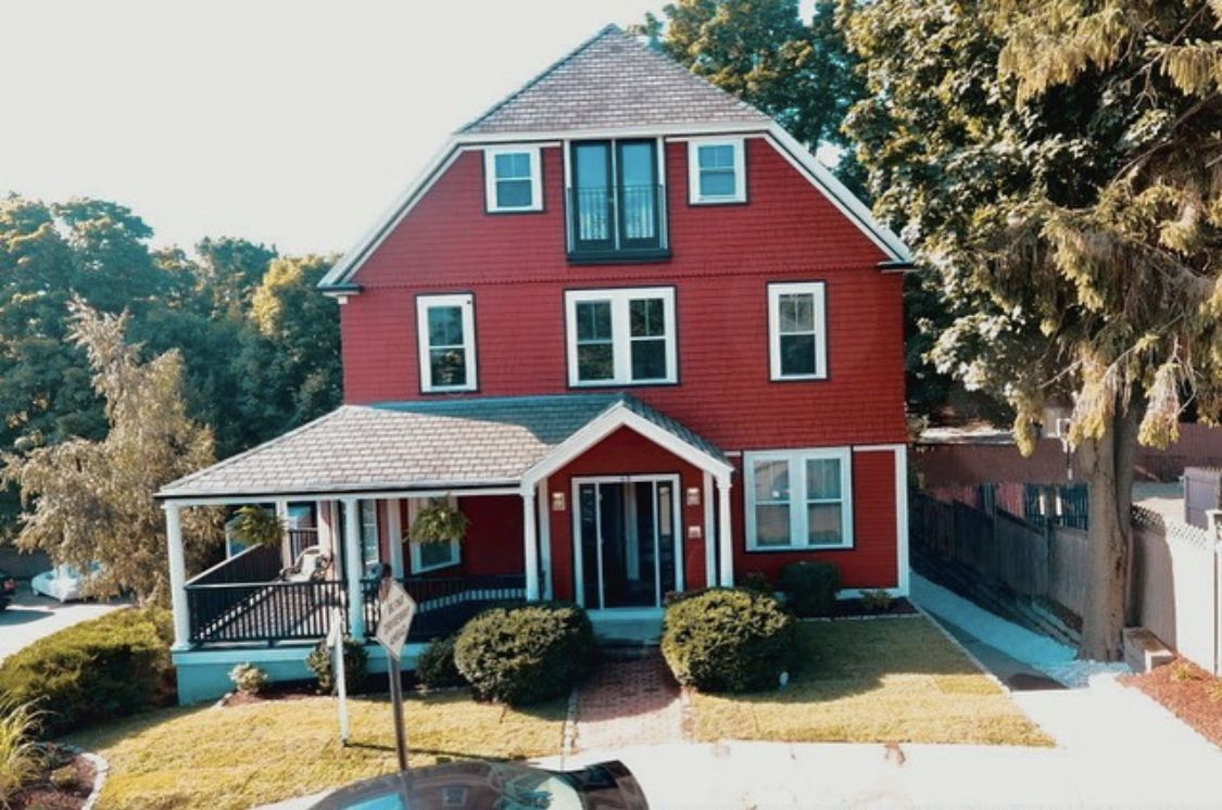 Red farmhouse exterior with a wraparound porch