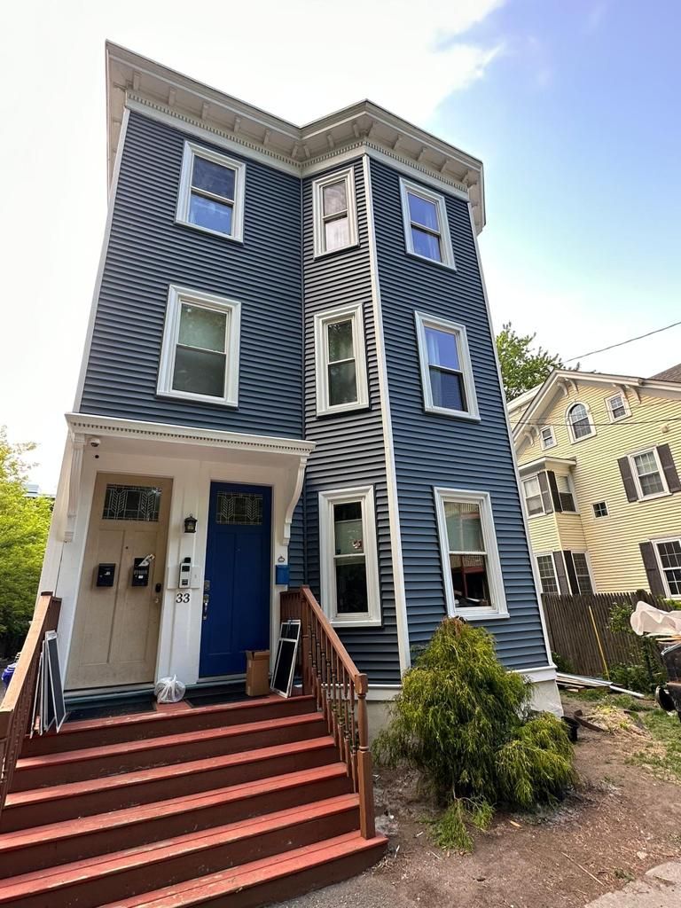 Three-story house with blue siding and red front stairs