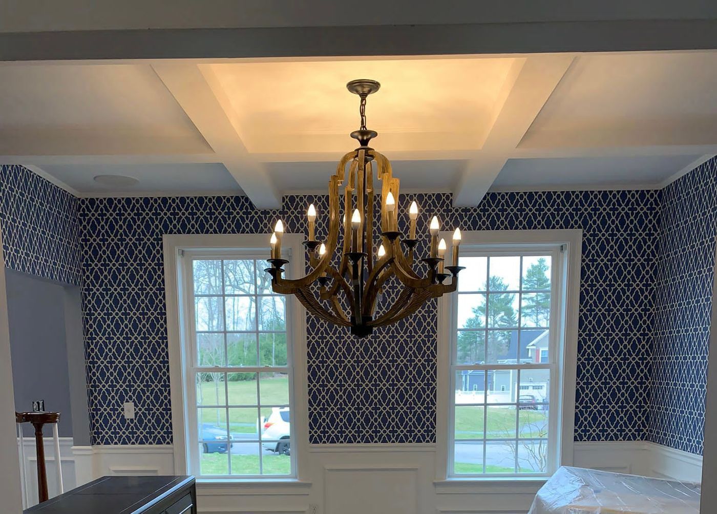 Dining room with patterned wallpaper, white trim and chandelier