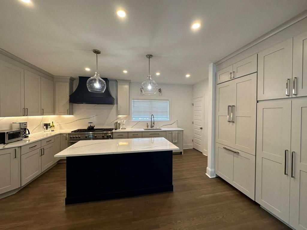White kitchen with a navy island after cabinet painting