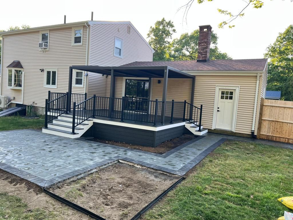 New backyard deck with black railings and paver patio